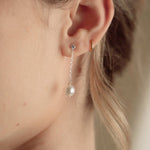 Close-up of a bride wearing a delicate crytal and pearl drop earring in silver with a pearl and crystal cluster pearl comb