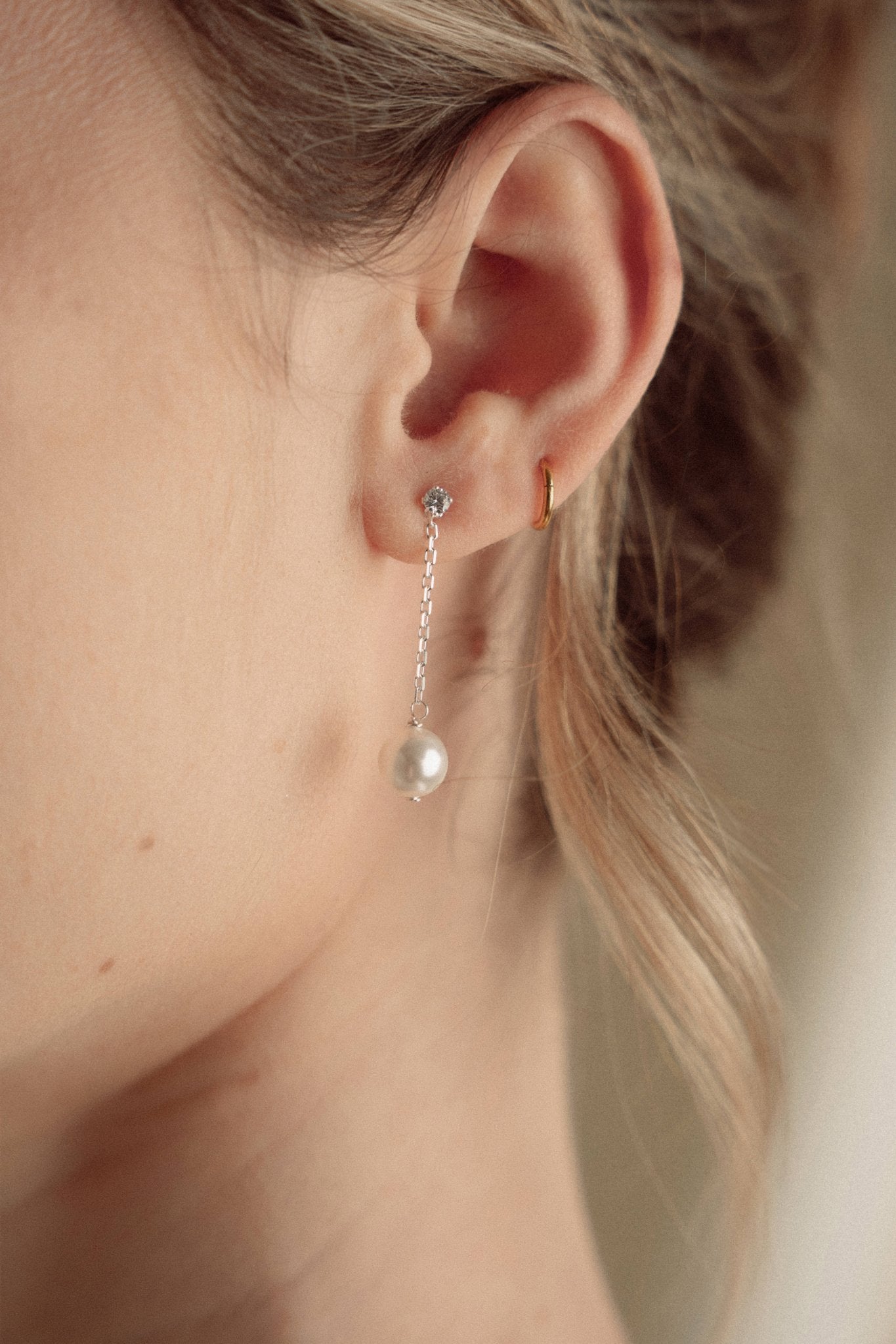 Close-up of a bride wearing a delicate crytal and pearl drop earring in silver with a pearl and crystal cluster pearl comb