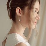 Close-up of a bride wearing a delicate crytal and pearl drop earring in silver with a pearl and crystal cluster pearl comb