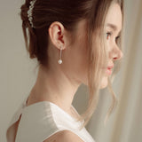 Close-up of a bride wearing a delicate crytal and pearl drop earring in silver with a pearl and crystal cluster pearl comb