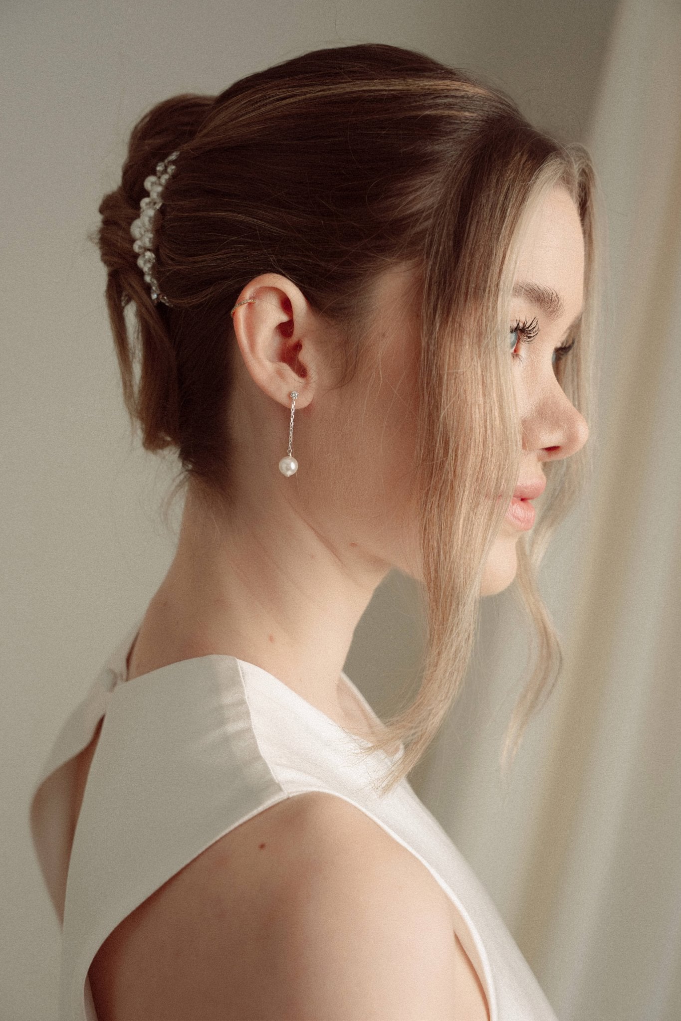 Close-up of a bride wearing a delicate crytal and pearl drop earring in silver with a pearl and crystal cluster pearl comb