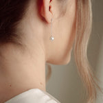 Close-up of a bride wearing a delicate crytal and pearl drop earring in silver with a pearl and crystal cluster pearl comb