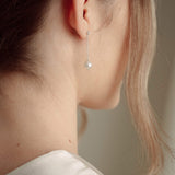Close-up of a bride wearing a delicate crytal and pearl drop earring in silver with a pearl and crystal cluster pearl comb