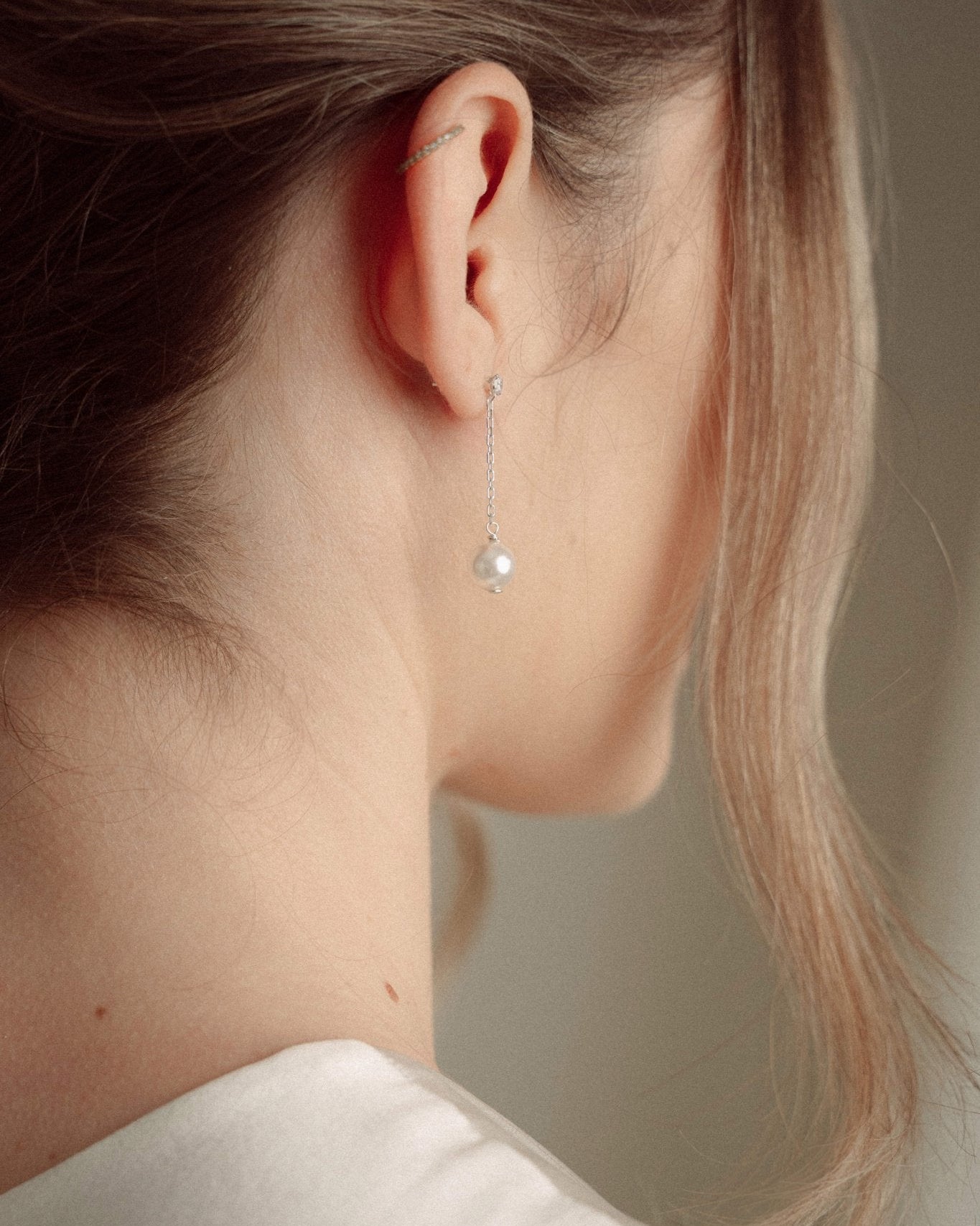 Close-up of a delicate silver crystal and vegan pearl drop earring with a pearl and crystal cluster bridal comb
