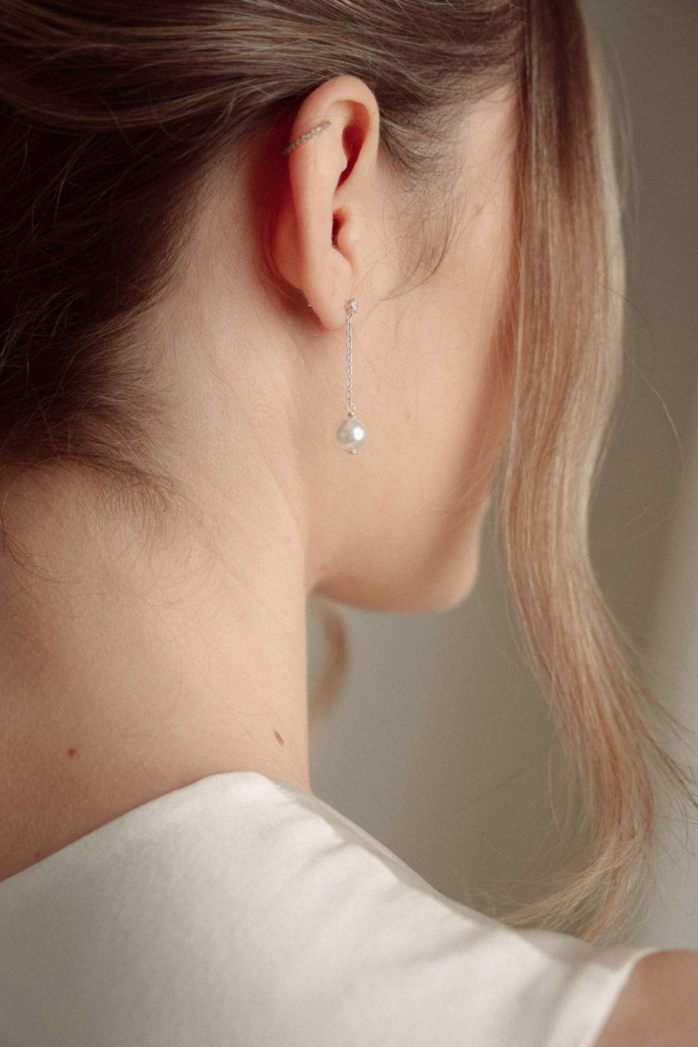 Close-up of a bride wearing a delicate crytal and pearl drop earring in silver with a pearl and crystal cluster pearl comb