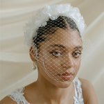 A black bride wears a full gathered birdcage veil with a silk flower padded headband