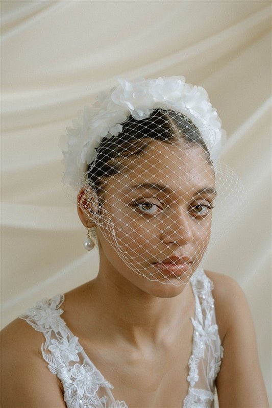 A black bride wears a full gathered birdcage veil with a silk flower padded headband