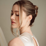 Bride wears pearl and crystal stud drop earrings with a small silver crystal comb with an elegant chignon updo