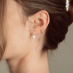 Bride wears pearl and crystal stud drop earrings with a small silver crystal comb with an elegant chignon updo