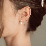 Bride wears pearl and crystal stud drop earrings with a small silver crystal comb with an elegant chignon updo