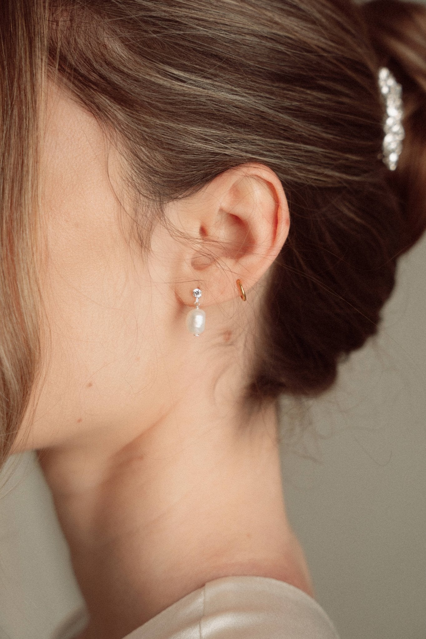 Bride wears pearl and crystal stud drop earrings with a small silver crystal comb with an elegant chignon updo