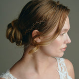 Model wears delicate gold leaf hair vine headband with low bun updo