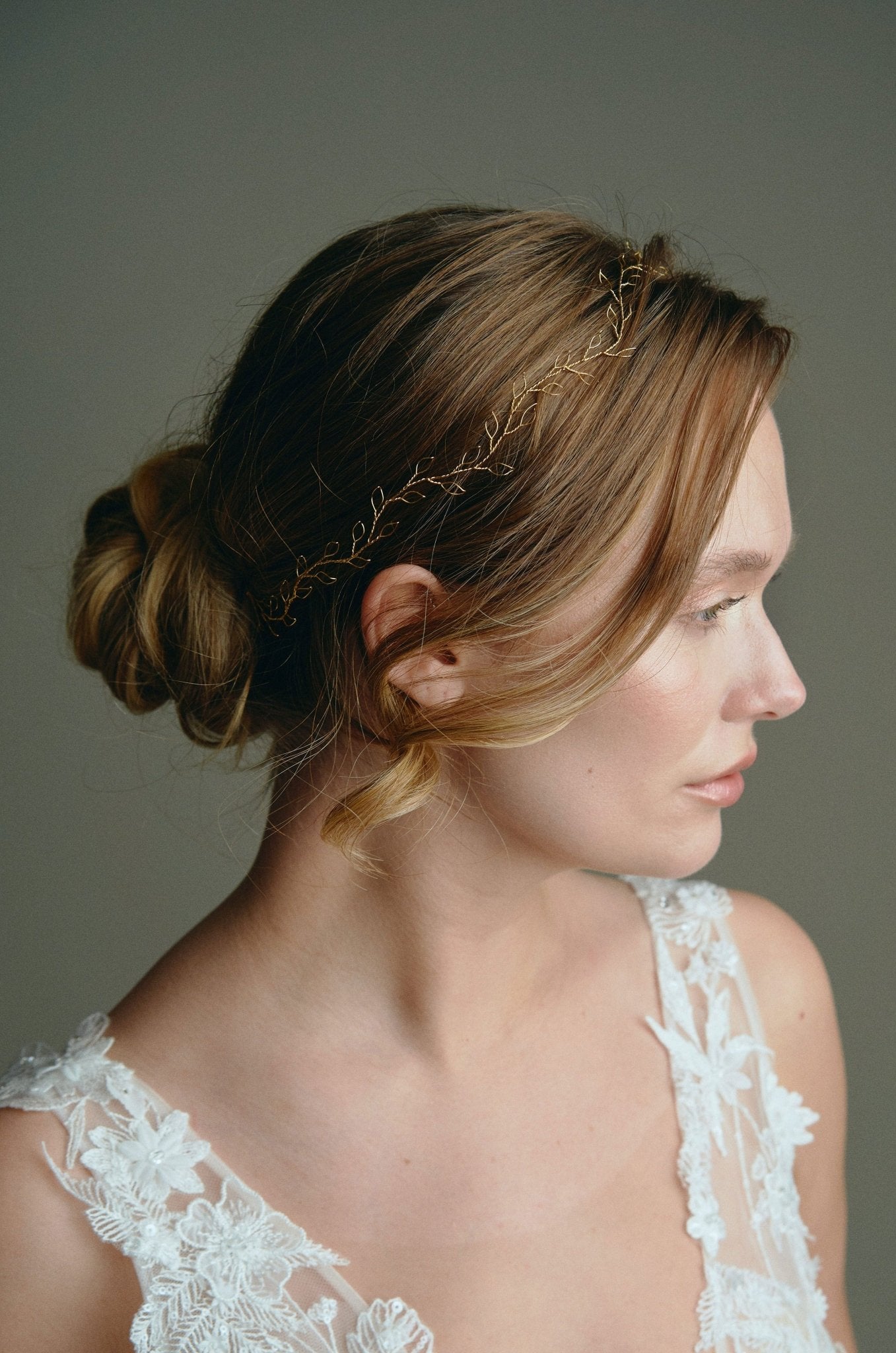 Model wears delicate gold leaf hair vine headband with low bun updo