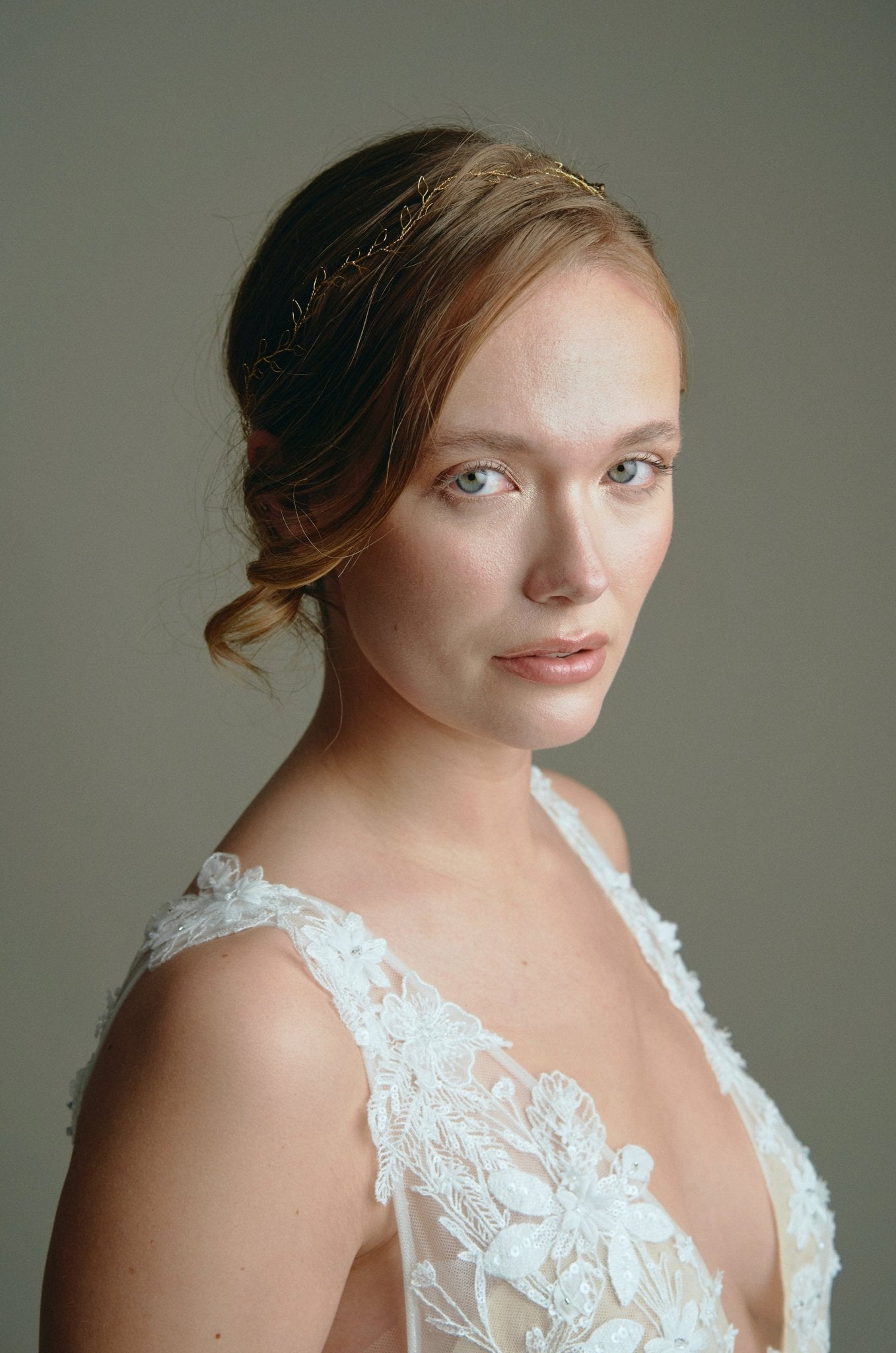 Model wears delicate gold leaf hair vine headband with low bun updo