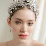 A bride wears a statement silver crown tiara with matching hair pins extending over the head.
