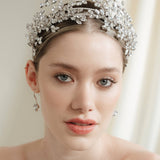 A bride wears a statement silver crown tiara with matching hair pins extending over the head.