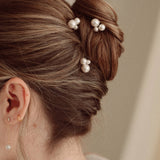 Bride wears pearl cluster hair pins and crystal and perl delicate drop earrings  with a silk gown and soft romantic chignon updo