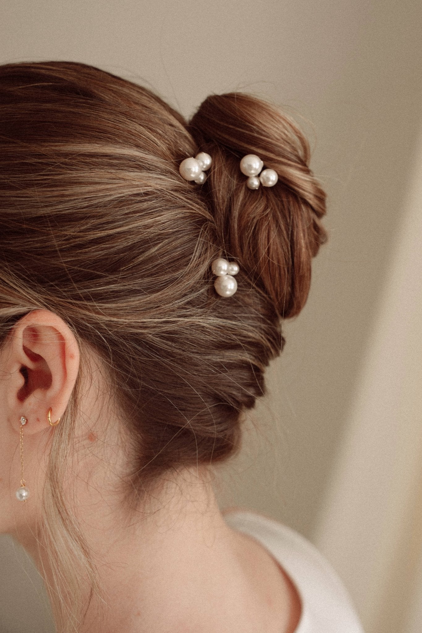 Bride wears pearl cluster hair pins and crystal and perl delicate drop earrings  with a silk gown and soft romantic chignon updo