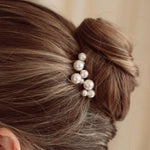 Bride wears pearl cluster hair pins with a soft romantic chignon updo