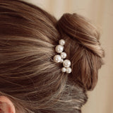 Bride wears pearl cluster hair pins with a soft romantic chignon updo