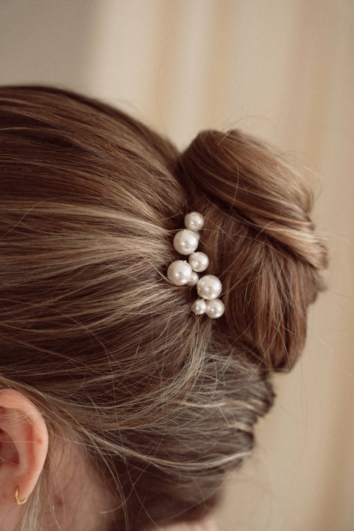 Bride wears pearl cluster hair pins with a soft romantic chignon updo