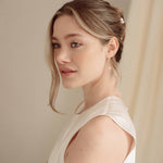 Bride wears pearl cluster hair pins and crystal and perl delicate drop earrings  with a silk gown and soft romantic chignon updo