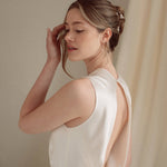 Bride wears pearl cluster earrings and crystal and perl delicate drop earrings  with a silk gown and soft romantic chignon updo