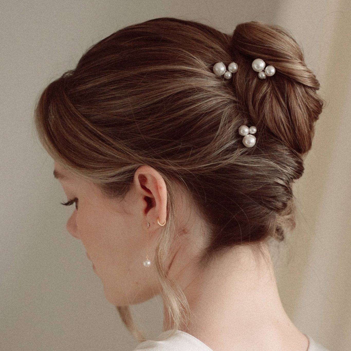 Side view of Ina gold crystal and vegan pearl drop earrings on a bride with pearl hair pins