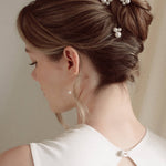 Bride wears pearl cluster hair pins and crystal and perl delicate drop earrings  with a silk gown and soft romantic chignon updo
