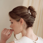 Bride wears pearl cluster hair pins and crystal and perl delicate drop earrings  with a silk gown and soft romantic chignon updo