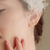 Bride wears an ivory tulle veil with face-framing silk flowers with coordinating silk flower and pearl long drop earrings