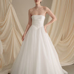 Bride wears an ivory tulle veil with face-framing silk flowers with coordinating silk flower and pearl long drop earrings