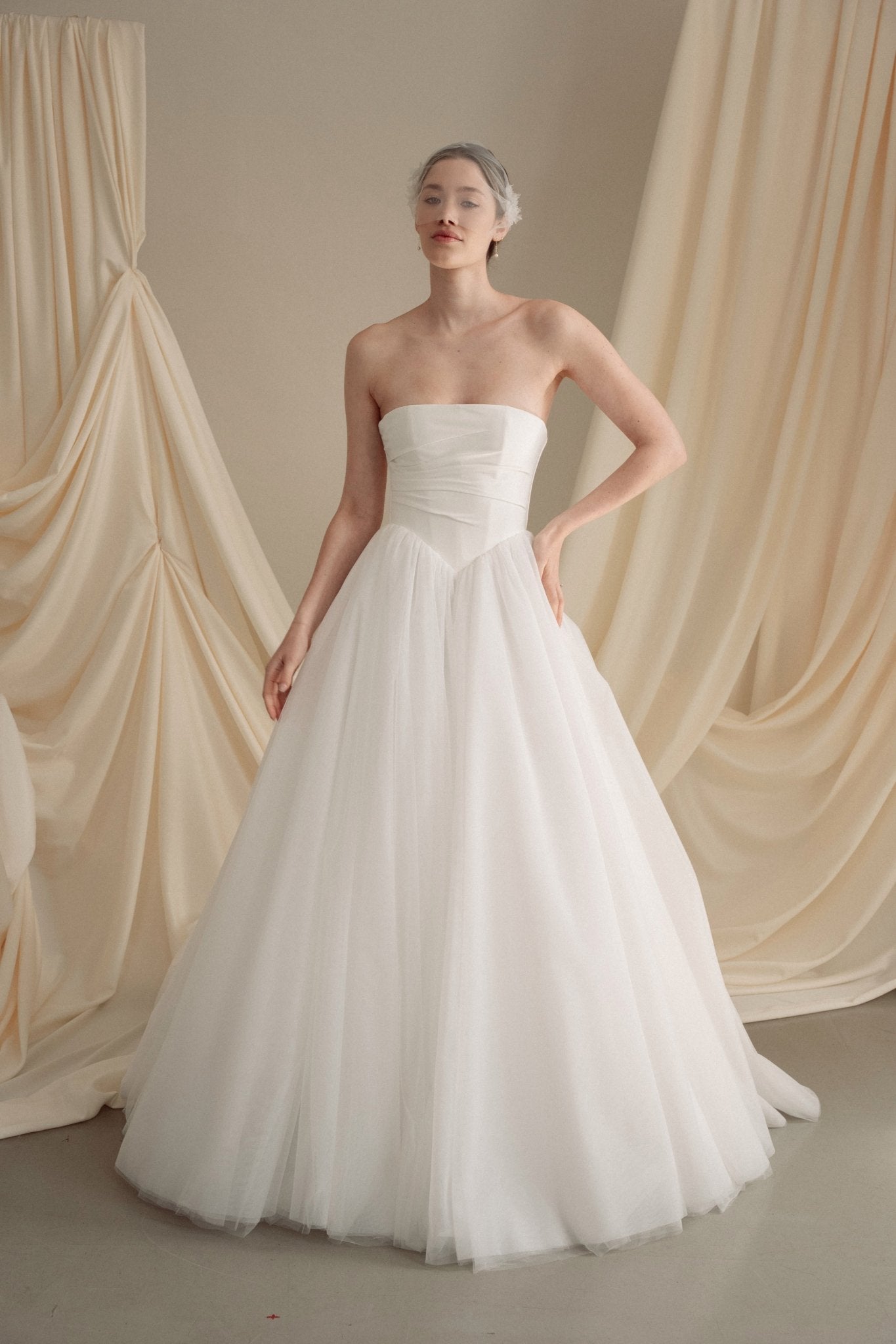 Bride wears an ivory tulle veil with face-framing silk flowers with coordinating silk flower and pearl long drop earrings
