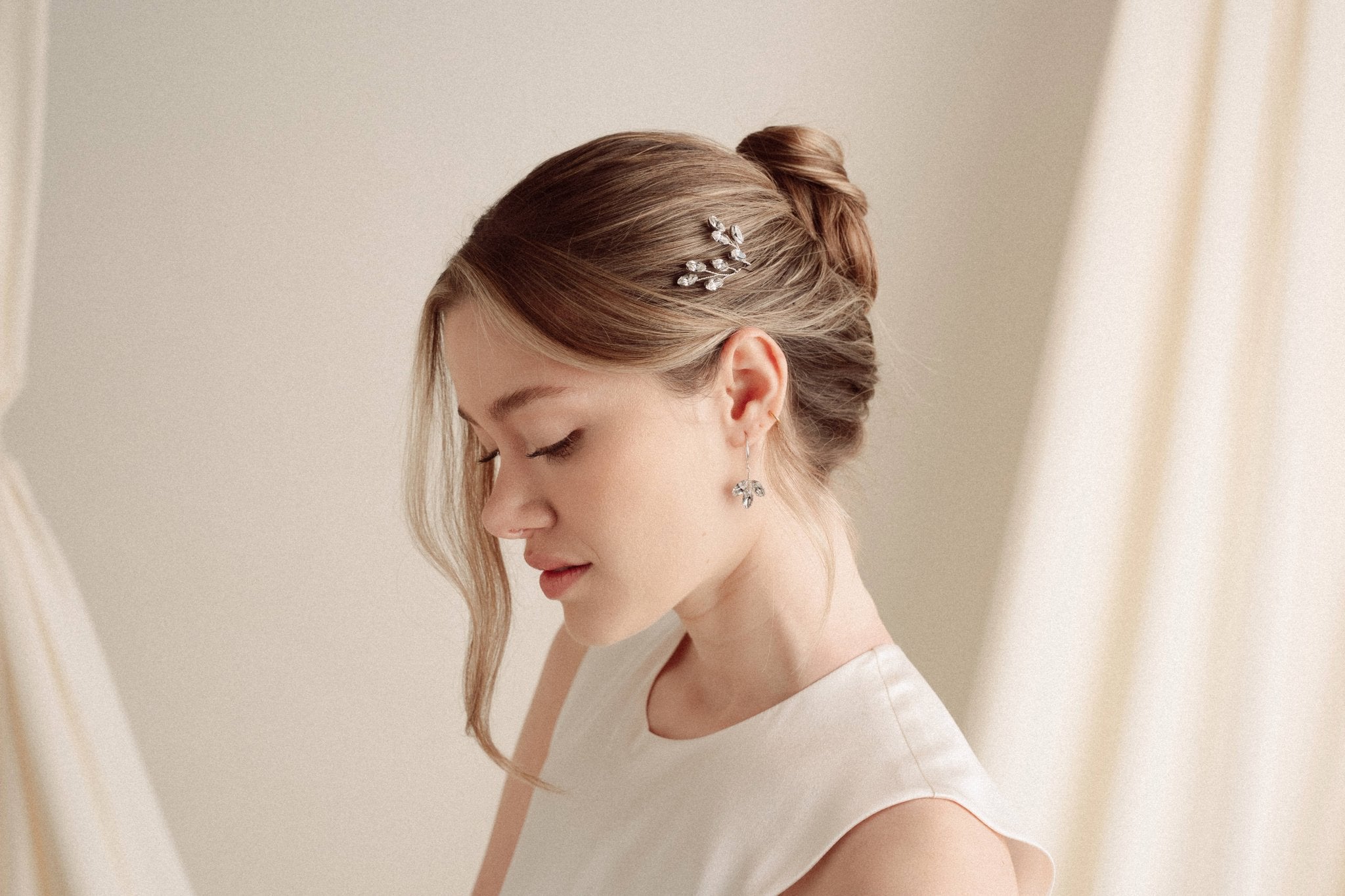 An elegant bride wears silver crystal drop earrings with matchching crytal hair pins