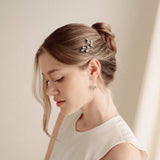 An elegant bride wears silver crystal drop earrings with matchching crytal hair pins