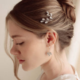 An elegant bride wears silver crystal drop earrings with matchching crytal hair pins