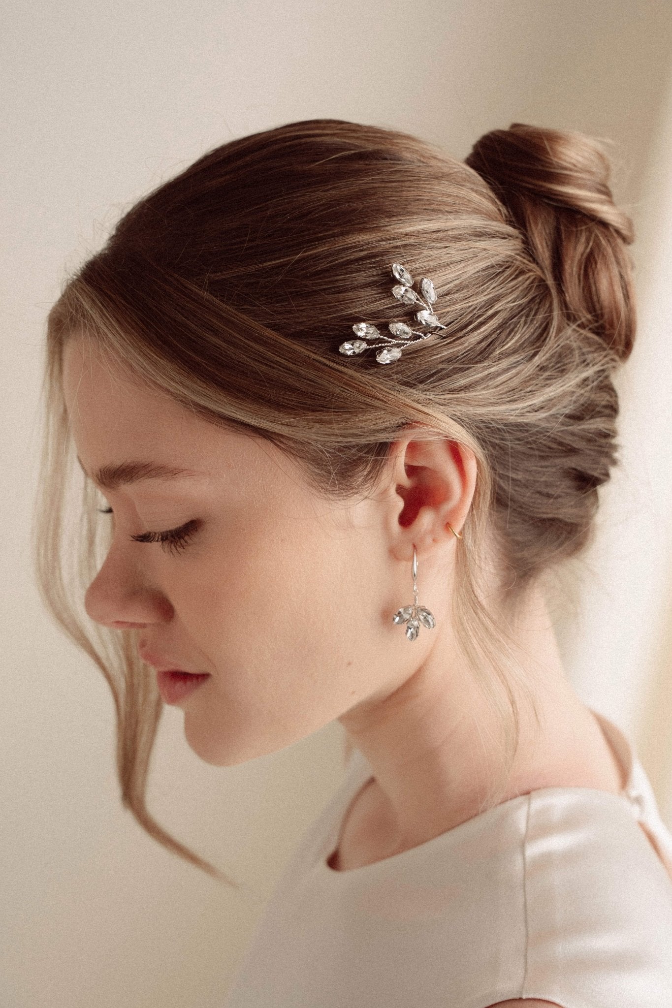 An elegant bride wears silver crystal drop earrings with matchching crytal hair pins