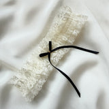 Lace garter with a black ribbon on a white fabric background