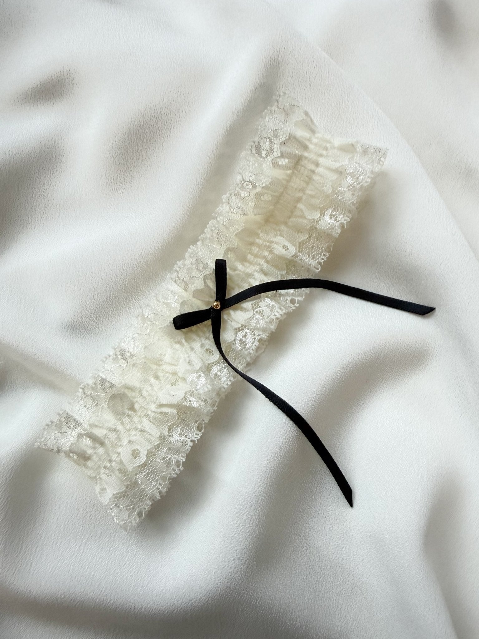 Lace garter with a black ribbon on a white fabric background
