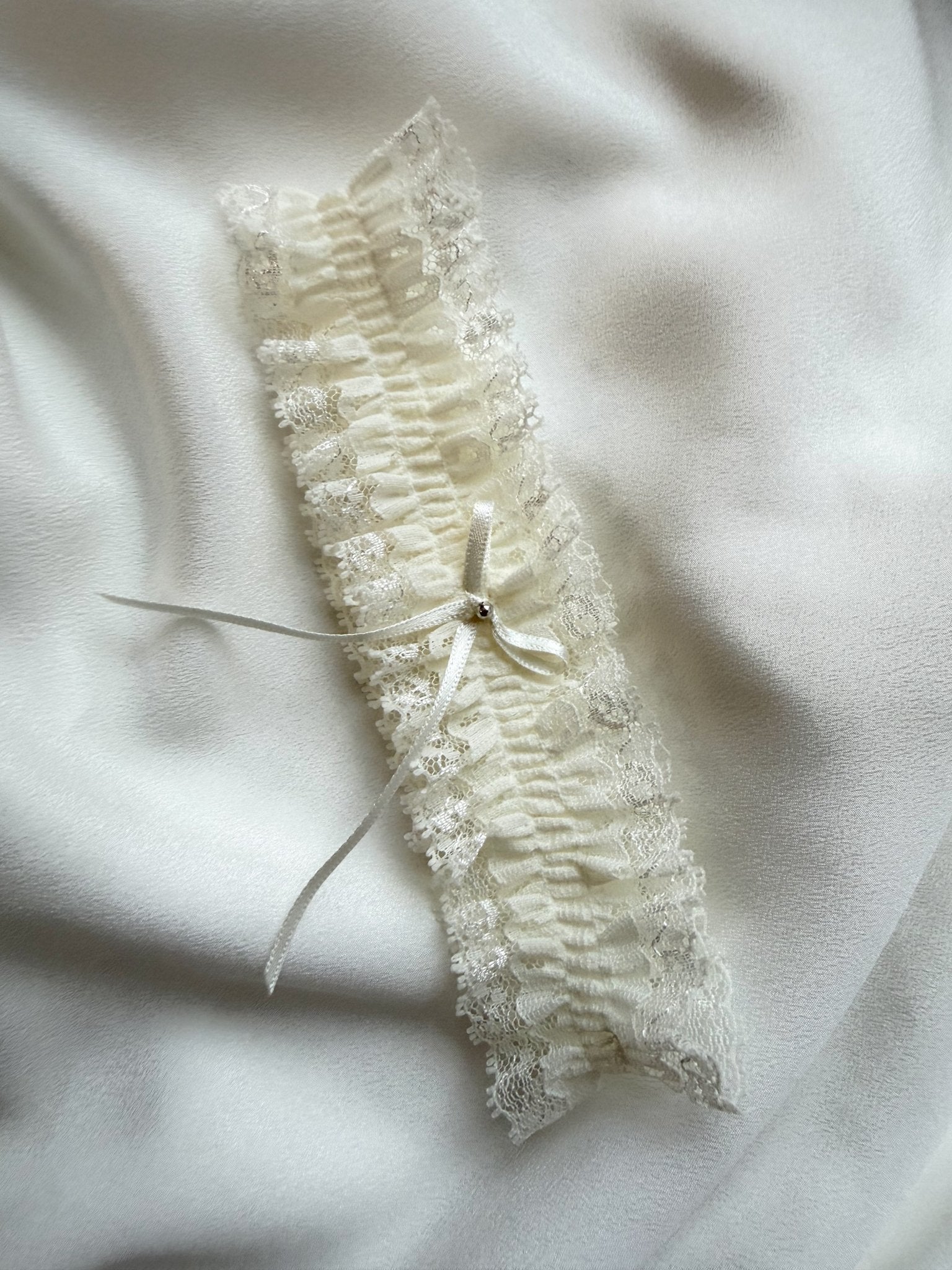 Lace garter with a bow on a soft white fabric background