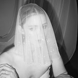 Bride wears a shaeer tulle drop micro veil with pearl and crystal embellishments 