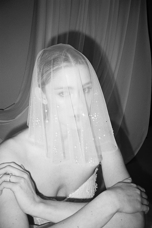 Bride wears a shaeer tulle drop micro veil with pearl and crystal embellishments 