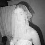 Bride wears a sheer tulle drop micro veil with pearl and crystal embellishments 