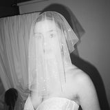 Bride wears a sheer tulle drop micro veil with pearl and crystal embellishments 