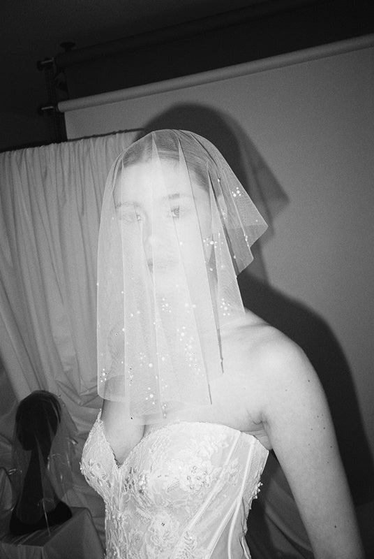 Bride wears a sheer tulle drop micro veil with pearl and crystal embellishments 