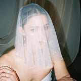 Bride wears a sheer tulle drop micro veil with pearl and crystal embellishments 