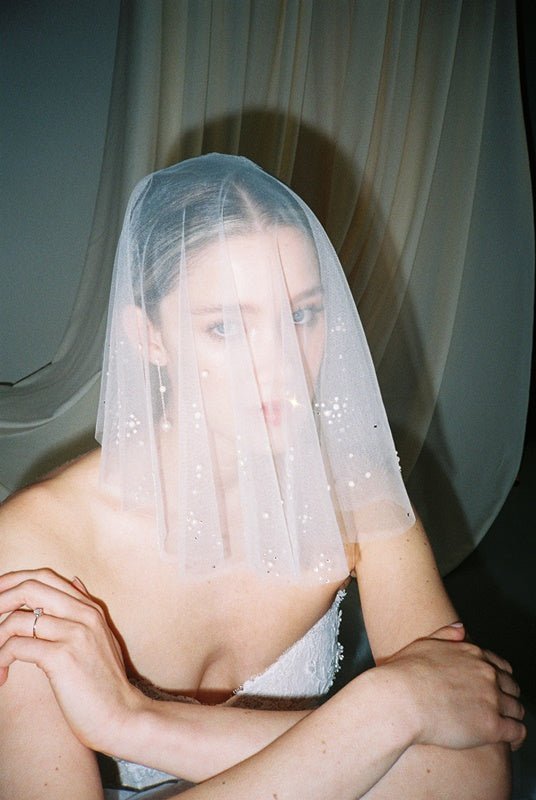 Bride wears a sheer tulle drop micro veil with pearl and crystal embellishments 