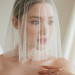 Bride wears a sheer tulle drop micro veil with pearl and crystal embellishments 