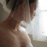 Bride wears a sheer tulle drop micro veil with pearl and crystal embellishments 