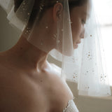 Bride wears a sheer tulle drop micro veil with pearl and crystal embellishments 